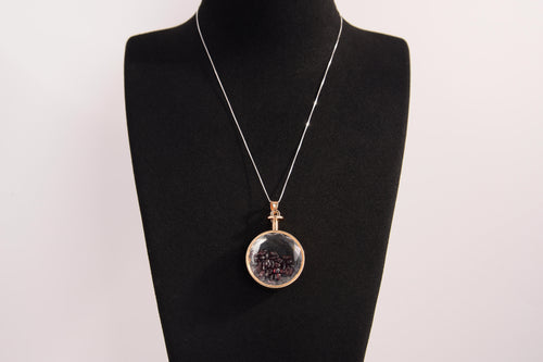 Raw Earth Crystals garnet pendant with a crystal-encased design, featuring natural garnet and gold-tone setting, promoting passion, vitality, and emotional strength.