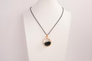 Raw Earth Crystals obsidian pendant with a crystal-encased design, featuring natural obsidian and gold-tone setting, promoting protection, grounding, and emotional balance.