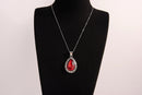 Raw Earth Crystals red agate pendant with a teardrop-shaped design, featuring natural red agate and an ornate silver-tone setting, promoting courage, vitality, and emotional strength.