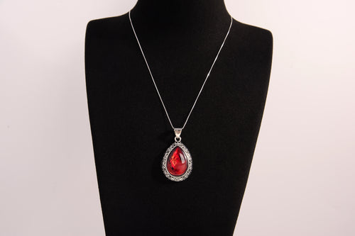 Raw Earth Crystals red agate pendant with a teardrop-shaped design, featuring natural red agate and an ornate silver-tone setting, promoting courage, vitality, and emotional strength.