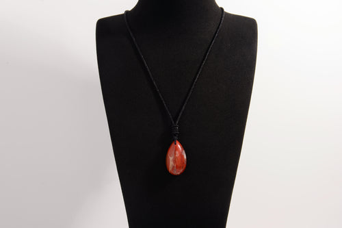 Raw Earth Crystals red jasper teardrop pendant on black cord, made from natural red jasper stone, supporting strength, courage, and emotional balance.