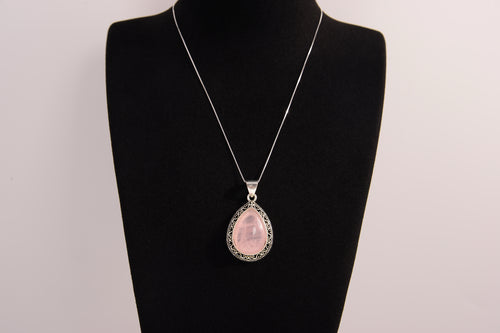 Raw Earth Crystals rose quartz pendant with a teardrop-shaped design, featuring natural rose quartz and an ornate silver-tone setting, promoting love, compassion, and emotional healing.