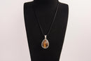Raw Earth Crystals tiger eye pendant with a teardrop-shaped design, featuring natural tiger eye and an ornate silver-tone setting, promoting confidence, focus, and protection.