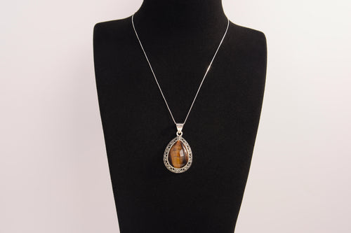 Raw Earth Crystals tiger eye pendant with a teardrop-shaped design, featuring natural tiger eye and an ornate silver-tone setting, promoting confidence, focus, and protection.