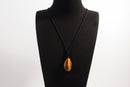 Raw Earth Crystals tiger eye teardrop pendant on black cord, crafted from natural tiger eye stone, promoting confidence, focus, and personal power.