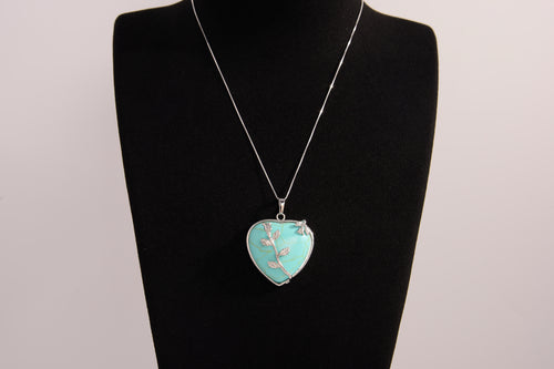 Raw Earth Crystals turquoise heart pendant with an elegant rose design, featuring a vibrant turquoise stone and a silver-tone vine with leaves, promoting communication, creativity, and emotional balance.