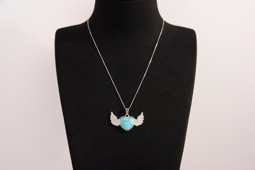 Raw Earth Crystals turquoise heart with wings necklace, featuring a vibrant blue-green heart-shaped stone adorned with delicate angelic wings, designed to promote communication, emotional balance, and spiritual protection.