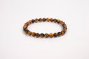 Tiger eye natural stone bead bracelet with polished round brown and gold beads on white background