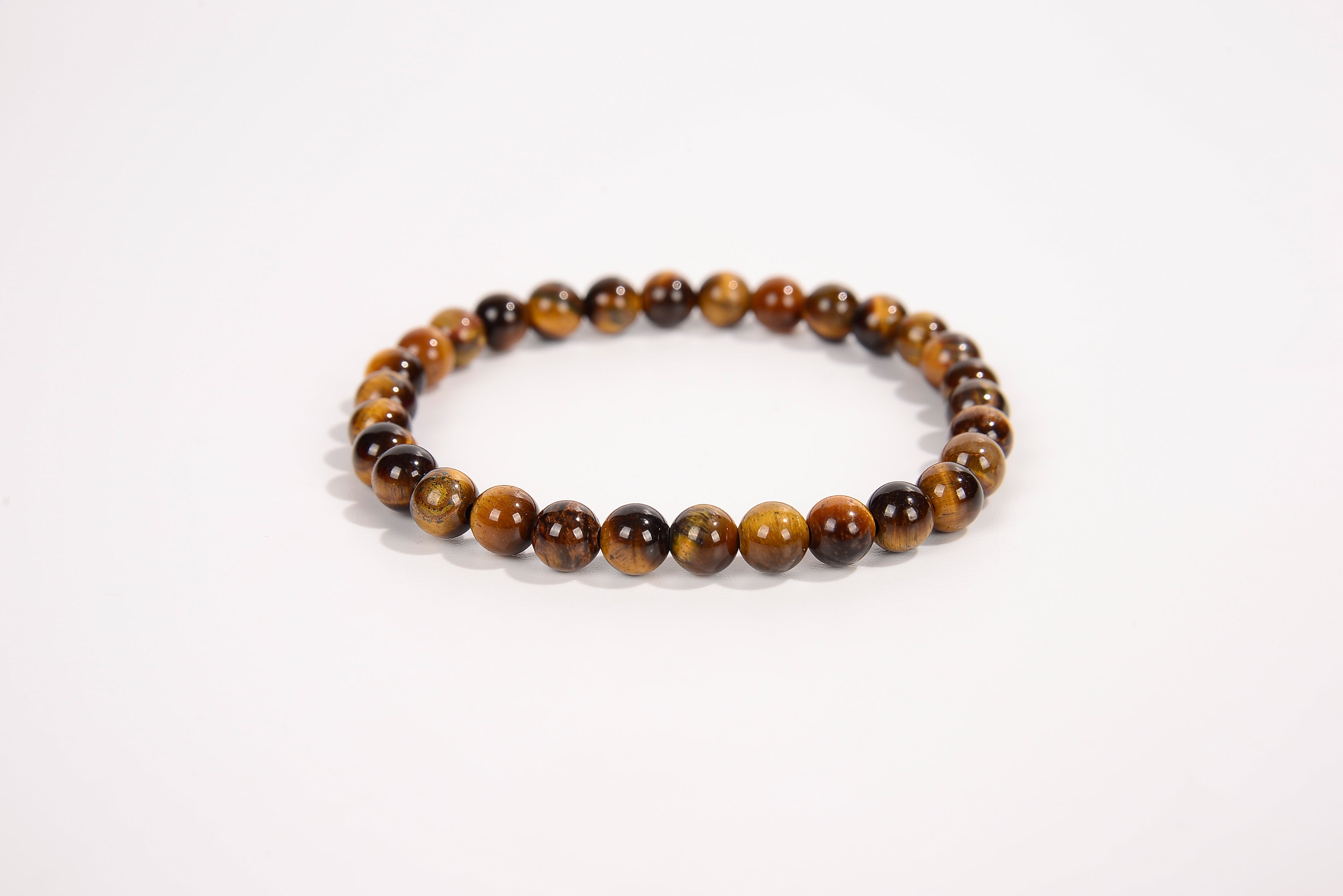 Tiger eye natural stone bead bracelet with polished round brown and gold beads on white background